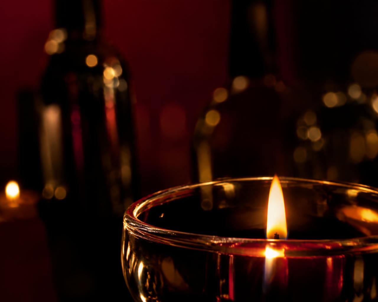 A candle flame reflected in the rim of a crystal glass